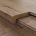 Close-up of a wooden surface with a textured light finish and a brown protective edge detail.