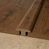 Close-up of a brown wood grain flooring transition piece, showcasing an intricate design and texture.