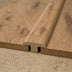 Close-up of medium-warm wood flooring with a seamless transition piece, showcasing natural grain patterns and textures.