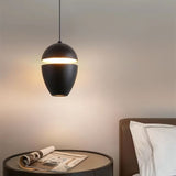"Aluminum pendant light in black with slit detail, providing ambient lighting over a bedside table in a bedroom."
