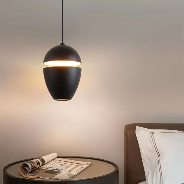 "Aluminum pendant light in black with slit detail, providing ambient lighting over a bedside table in a bedroom."