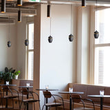 "Sleek aluminum and glass pendant light in black finish, emitting soft ambient glow, perfect for modern dining areas."