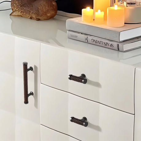 "Braided leather knobs and pull bar handles with a luxurious finish on a modern white cabinet."