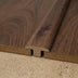 Close-up of wood-plastic composite flooring showing a T-molding transition piece in a rich wood finish.