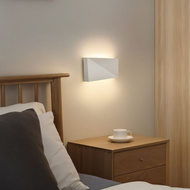 "minimalist wall lamp in bedroom, white aluminum fixture, ambient lighting near wooden furniture, geometric design"