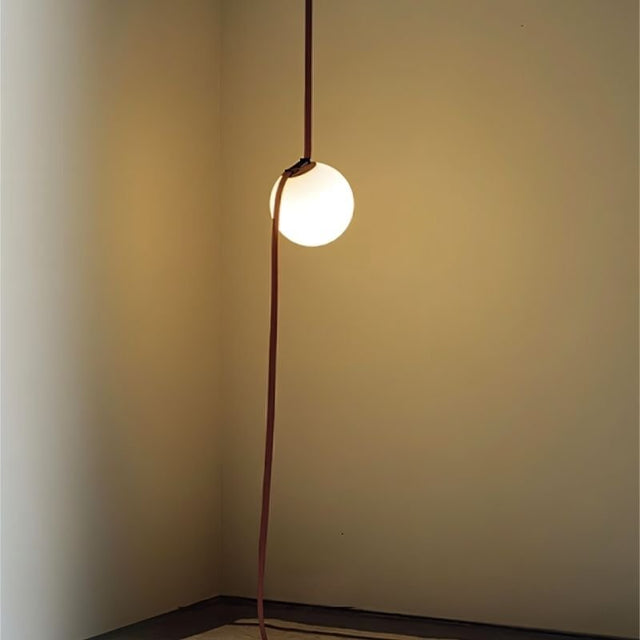 "close-up of suspended glowing glass orb with cloth-covered tensioned support"