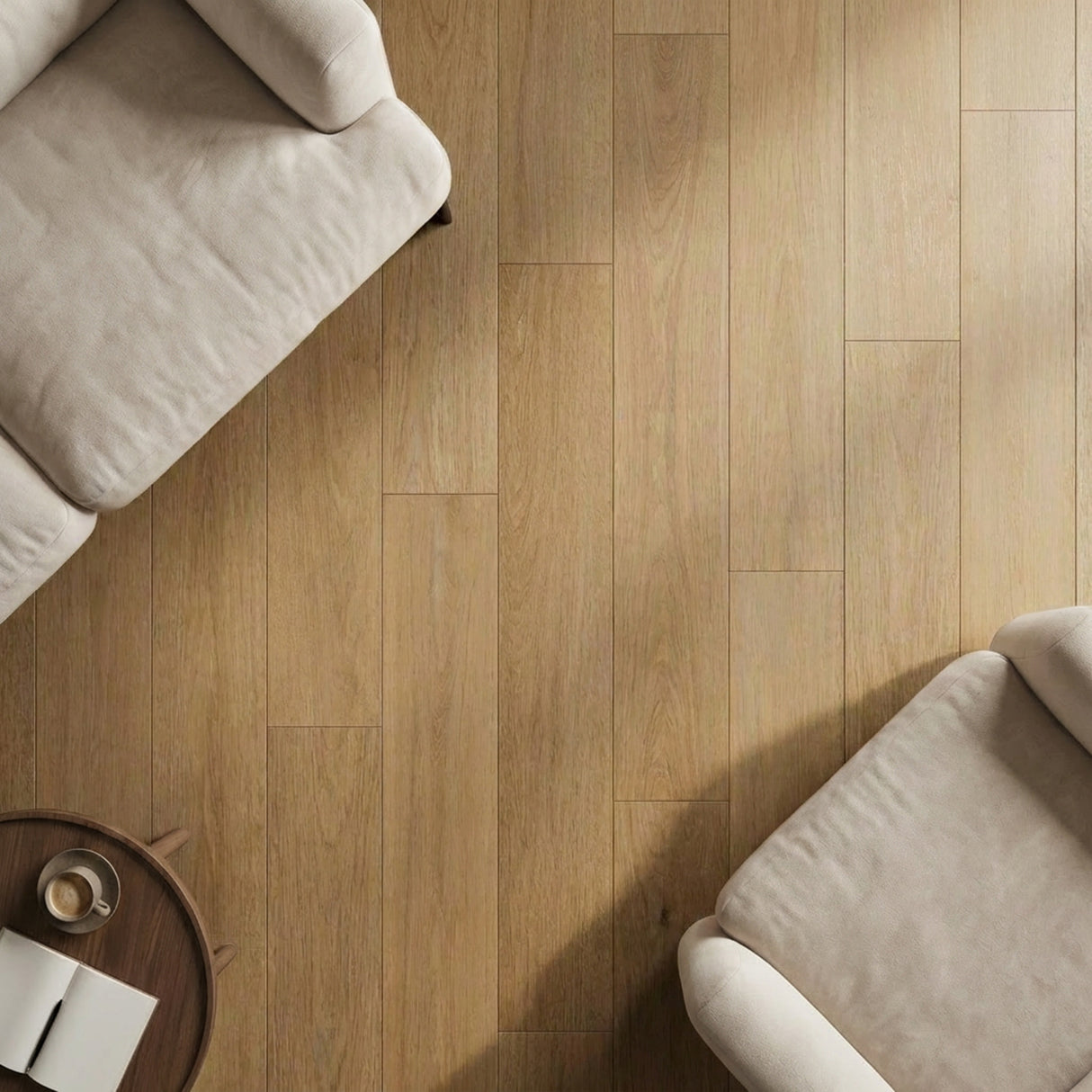 Two light-colored couches on warm-toned wooden floor in a cozy living area with a round coffee table.