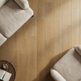 Two light-colored couches on warm-toned wooden floor in a cozy living area with a round coffee table.