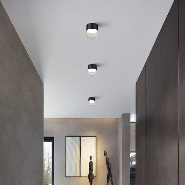 "Three black Hafra ceiling lights suspended above a dining table, creating a sophisticated lighting setup with their aluminum and glass materials for balanced, warm lighting."