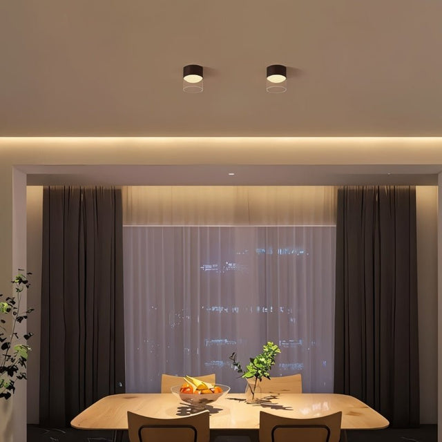 "The Hafra ceiling light installed above a dining table, providing soft, ambient light in a modern space, constructed from durable aluminum, glass, and acrylic for even light distribution."