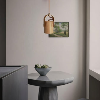 "The Helis Pendant Light in a modern living space, showcasing its minimalist wooden design and warm ambient light above a contemporary table and decorative bowl, crafted from durable wood."