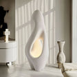 "Izbu Floor Lamp illuminated by natural sunlight, showcasing its sculptural design, smooth curves, hollow details, and polystyrene material in a modern setting."