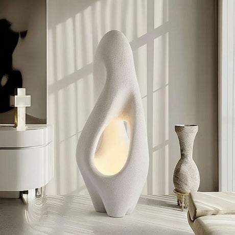 "Izbu Floor Lamp illuminated by natural sunlight, showcasing its sculptural design, smooth curves, hollow details, and polystyrene material in a modern setting."