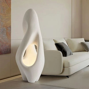 "Izbu Floor Lamp in a modern living room, showcasing its sculptural design, smooth curves, and hollowed details made from polystyrene material."