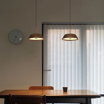 "Close-up of wood and copper pendant lights above a dining table, showcasing warm, ambient lighting and sleek design."