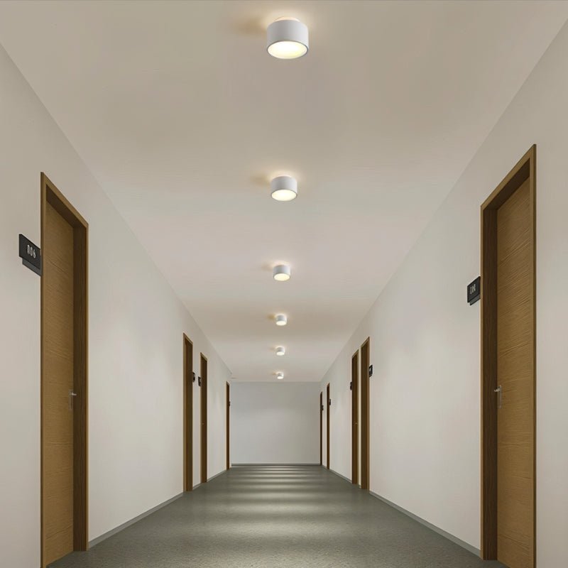 "White aluminum ceiling lights illuminating a long hallway, modern design with ambient lighting."