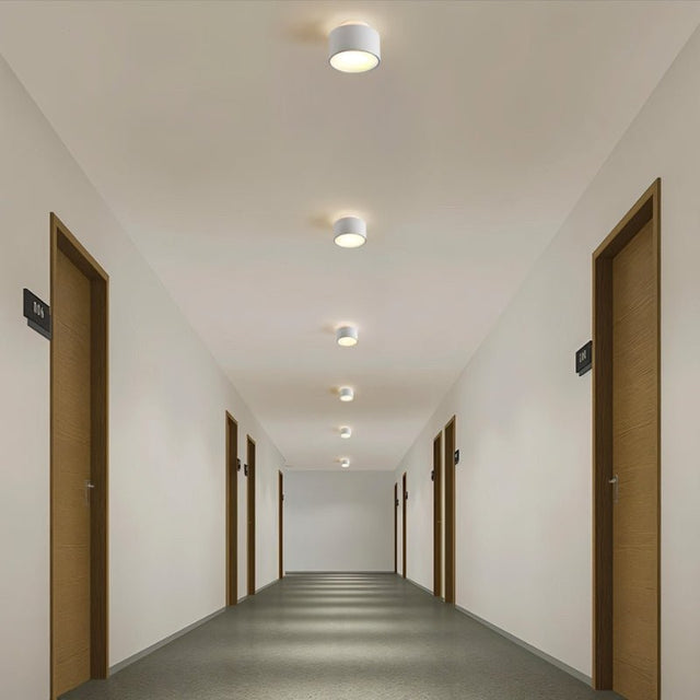 "White aluminum ceiling lights illuminating a long hallway, modern design with ambient lighting."