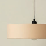 "Close-up of fabric shade with smooth finish, minimalist hanging light, black fixture detail, soft glow"