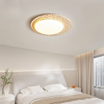 "Ceiling light fixture featuring natural travertine and marble diffuser, providing warm ambient lighting in a modern bedroom."