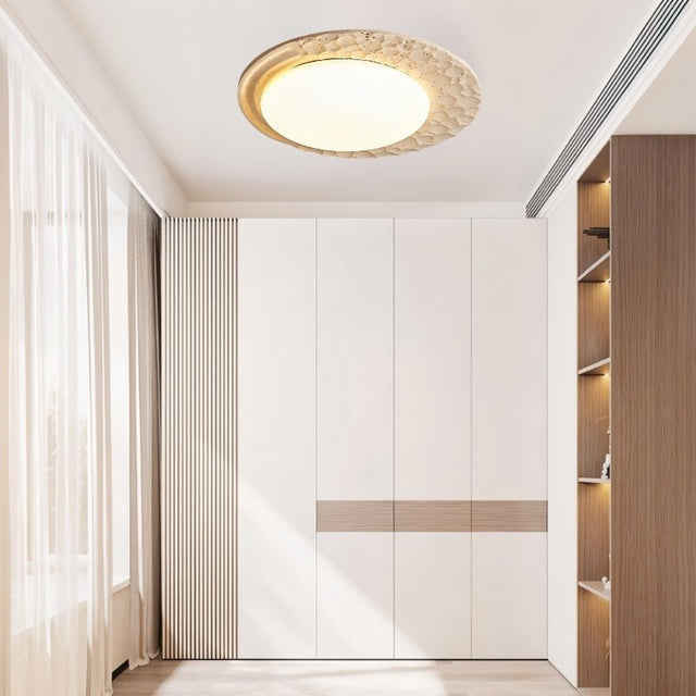 "Ceiling lamp with travertine design and marble diffuser installed in a bright wardrobe room, emitting soft natural light."