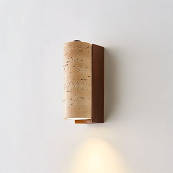 "Close-up of a travertine wall lamp with a cylindrical shade and wooden base, showing the texture of the stone and warm light."