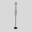 "The Lyris floor lamp with a black metal base and stacked translucent glass orbs emits a soft, ambient glow, making it a modern addition to any space. Constructed from metal, glass, and acrylic materials."
