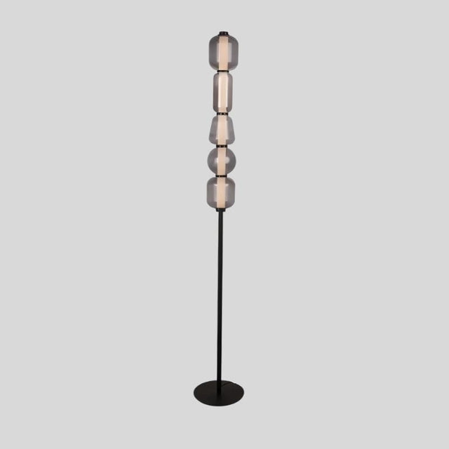 "The Lyris floor lamp with a black metal base and stacked translucent glass orbs emits a soft, ambient glow, making it a modern addition to any space. Constructed from metal, glass, and acrylic materials."