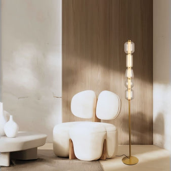 "The Lyris floor lamp features a sleek gold metal base with stacked translucent glass orbs, providing a warm, ambient glow. Made of metal, glass, and acrylic, this modern light fixture enhances contemporary spaces."