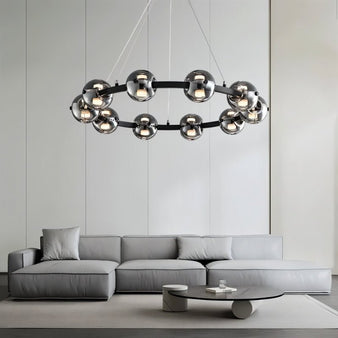 "Modern chandelier with smoked glass orbs hanging above a grey sofa in a living room setting."