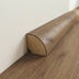 Curved wooden trim with a natural finish against a wall, complementing a wooden floor surface.
