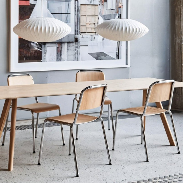 "Minimalist dining space featuring twin modern pendant lights above a wooden table with sleek metal-framed chairs."