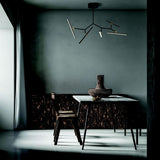 "Chandelier with artistic design in a moody room, featuring angular black arms and bright LED lights, ideal for modern interiors."