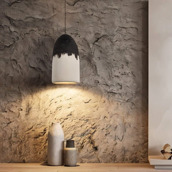 "Pendant lamp with two-tone finish illuminating textured wall and decorative vases"