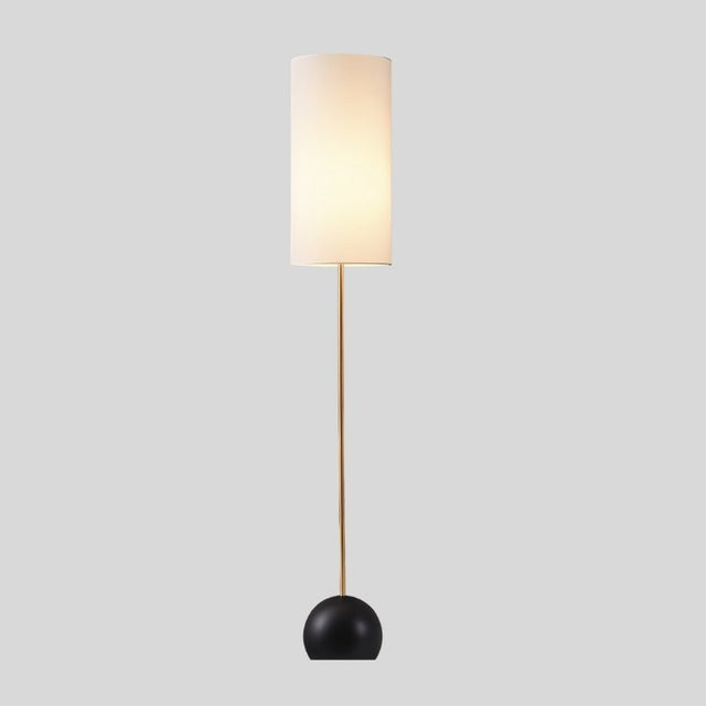 "Isolated view of floor lamp, cylindrical fabric shade, slim wooden pole."