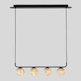 "Front view of the Ostra pendant lamp with four alabaster and aluminum spheres suspended from a sleek black frame, adding a contemporary touch to modern interiors."