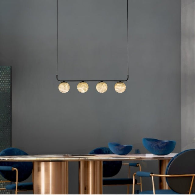 "Modern pendant lamp featuring alabaster and aluminum materials, hanging above a sleek dining table with blue chairs, providing a warm, ambient glow to a contemporary living space."