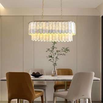 "Linear chandelier with layered shell panels and gold accents, hanging above a dining table in a modern dining room."