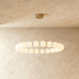 Agnes chandelier featuring an elliptical shape with frosted globes and a brass finish, suspended from a ceiling mount.