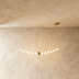 A modern pendant chandelier with a curved brass finish and white globes, elegantly suspended from the ceiling.