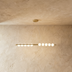 Modern brass chandelier with circular bulbs, suspended from the ceiling in a warm, textured room. Elegant and minimal design.