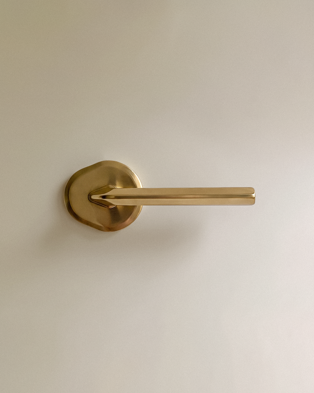 Enzo Door Handle in Unlacquered Brass, on a plain background