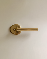 Enzo Door Handle in Unlacquered Brass, on a plain background