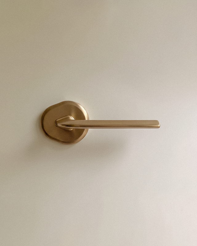 Enzo Door Handle in Satin Brass, on a plain background