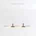 Three-light pendant fixture with white cylindrical shades and wood accents suspended from white canopy against neutral background.