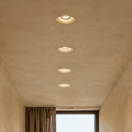 Beige ceiling with recessed lights and a window with curtains.