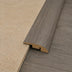 Curved transition strip in a wood-like finish connecting light-colored textured surface and darker flooring.