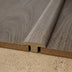 Gray wood flooring with a T-molding transition piece, showcasing a smooth finish and natural wood grain texture.