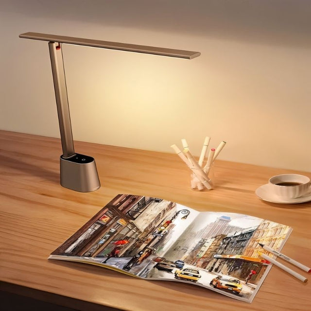 "Stylish aluminum and polycarbonate table lamp illuminating a book on a desk, enhancing workspace ambiance."