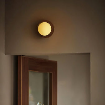 "Minimalist wall lamp with warm lighting, wood and glass design, mounted above a wooden door in a hallway"