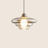 "Dome-shaped Thuli pendant light with a sleek glass shade and metallic accents for contemporary interiors."